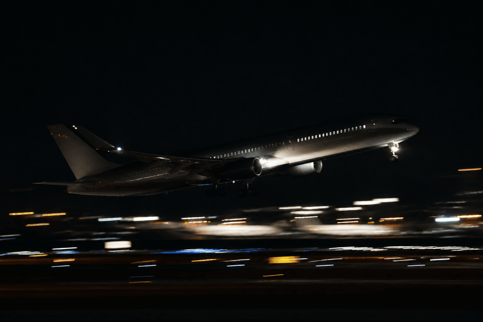 An airplane lifting off over runway lights
